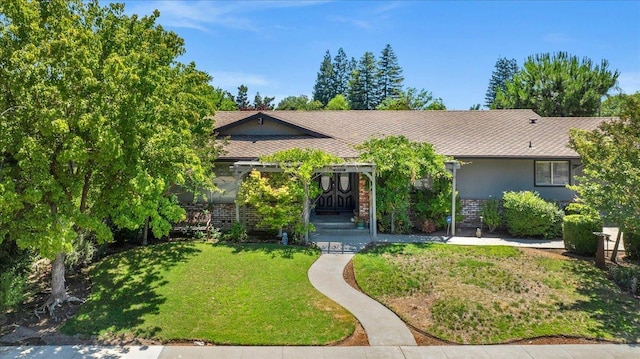 view of front of house featuring brick siding, stucco siding, and a front yard