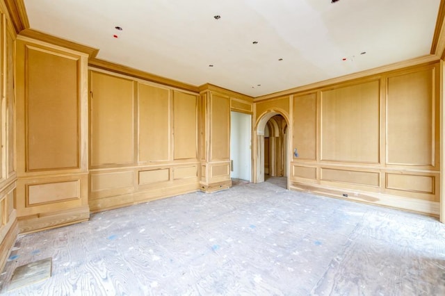 empty room featuring arched walkways and a decorative wall