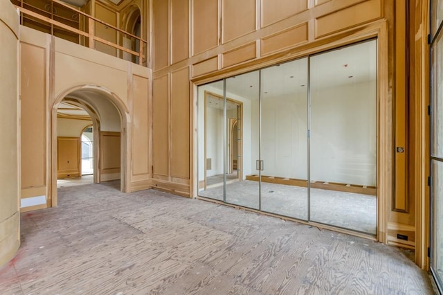 empty room featuring arched walkways, a high ceiling, and a decorative wall