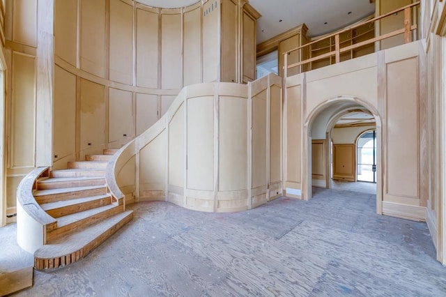 stairway featuring arched walkways and a decorative wall