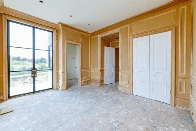 unfurnished bedroom with access to outside, a decorative wall, and crown molding