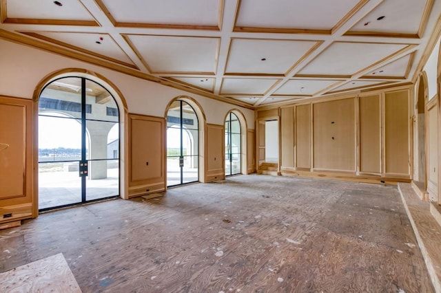 empty room featuring a healthy amount of sunlight, coffered ceiling, and french doors