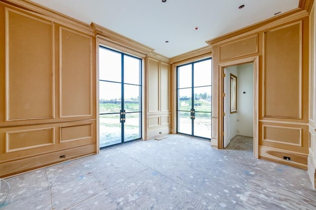 spare room featuring ornamental molding, french doors, and a decorative wall