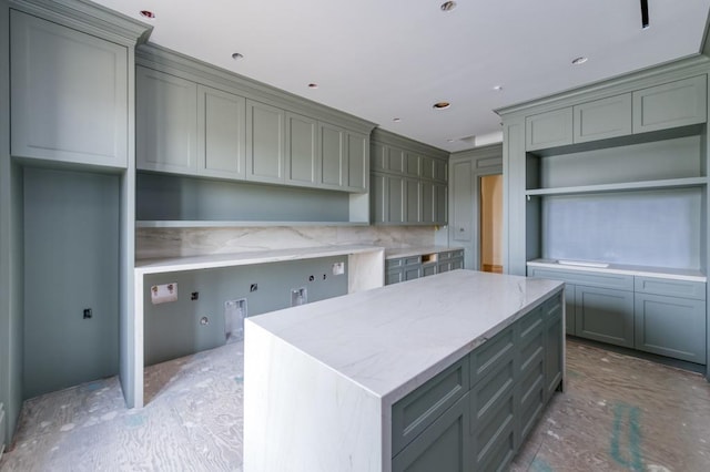 kitchen with light stone countertops, gray cabinets, and a center island