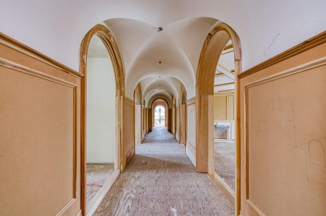 corridor with lofted ceiling and arched walkways