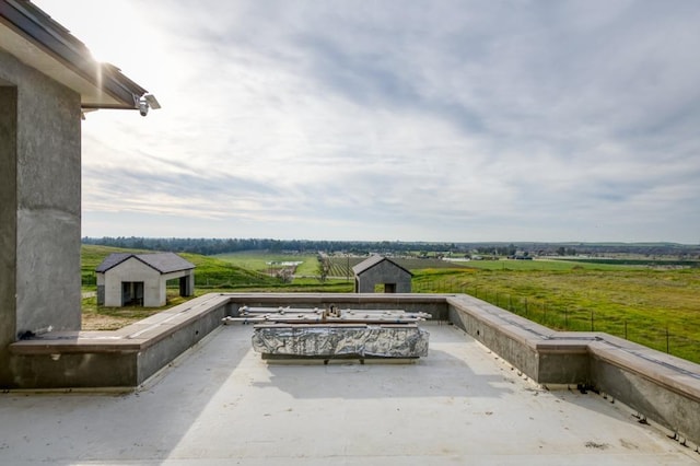 view of patio with an outbuilding, a shed, and a rural view