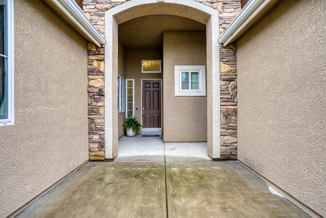 entrance to property featuring stone siding and stucco siding