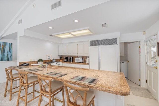 39118 Lake Dr, Bass Lake, CA 93604 - kitchen with paneled built in fridge, white microwave, a kitchen bar, white cabinetry, and a peninsula