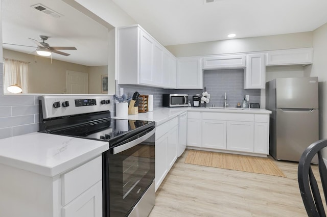 kitchen with visible vents, a ceiling fan, a sink, appliances with stainless steel finishes, and white cabinets