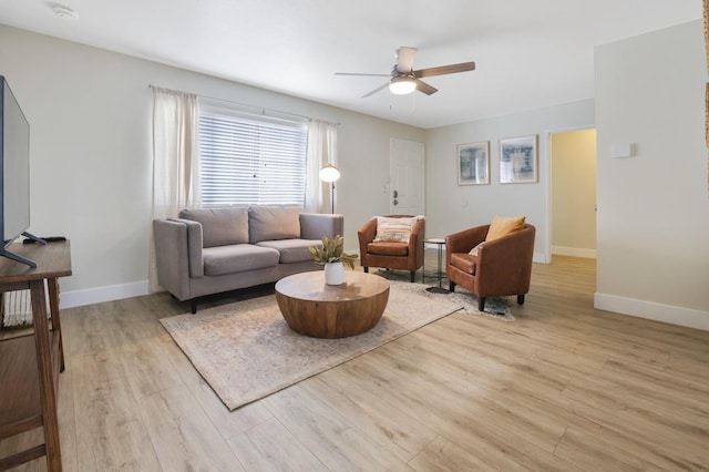 living area with baseboards, wood finished floors, and a ceiling fan