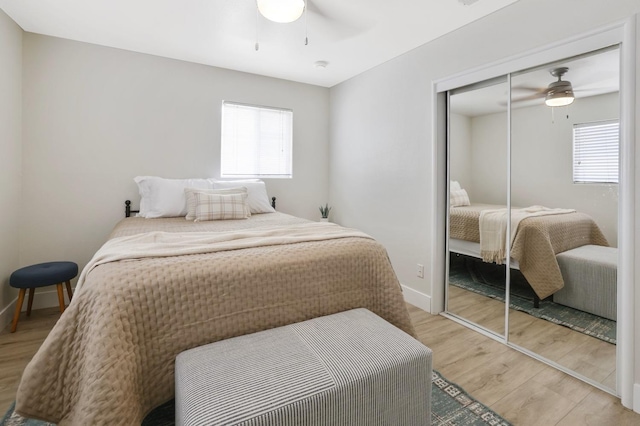 bedroom featuring a closet, multiple windows, baseboards, and light wood finished floors