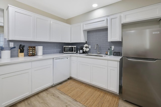 kitchen with a sink, stainless steel appliances, light wood-style flooring, and light countertops