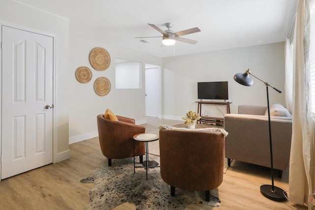 living area featuring light wood-style flooring, baseboards, visible vents, and ceiling fan