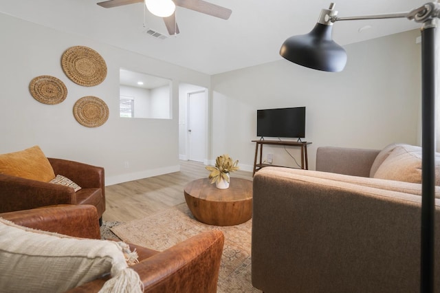 living room featuring baseboards, wood finished floors, visible vents, and ceiling fan