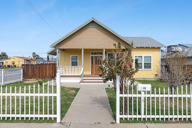 bungalow with a porch, roof with shingles, a front lawn, and fence