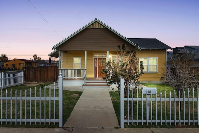 bungalow-style house with a fenced front yard, covered porch, and a shingled roof