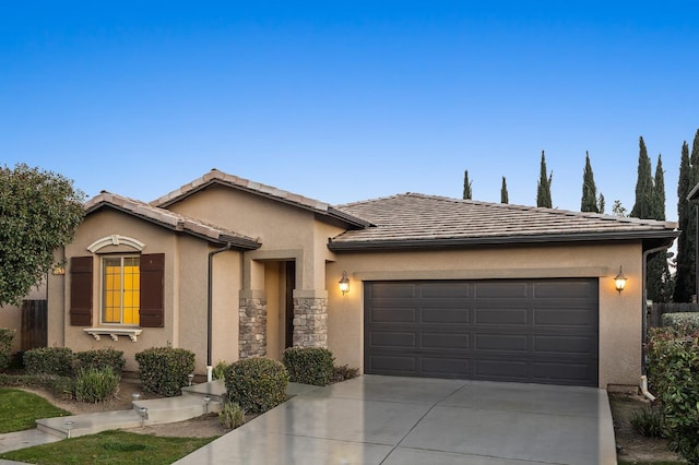 view of front of home featuring a tile roof, stucco siding, an attached garage, stone siding, and driveway