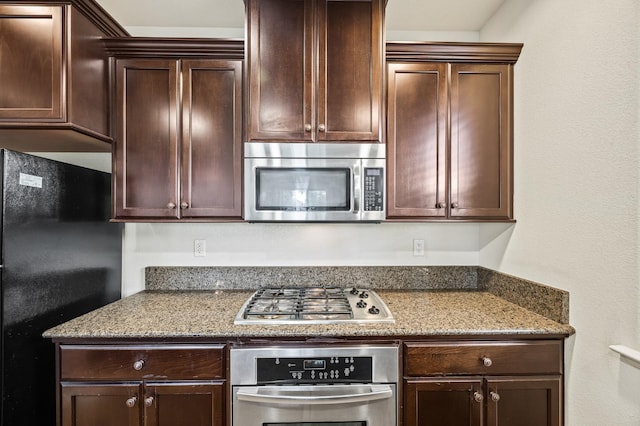 kitchen featuring stone counters, appliances with stainless steel finishes, and dark brown cabinets