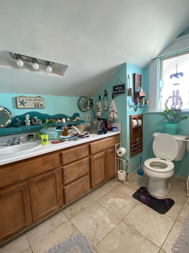 bathroom with double vanity, toilet, vaulted ceiling, a sink, and tile patterned flooring