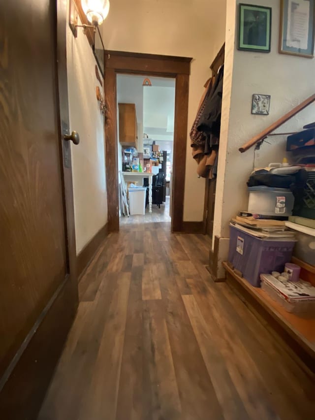 hallway featuring baseboards and dark wood-type flooring