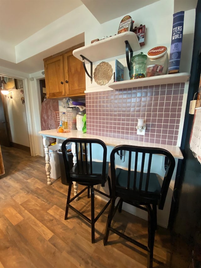 kitchen featuring brown cabinets, open shelves, light countertops, backsplash, and wood finished floors