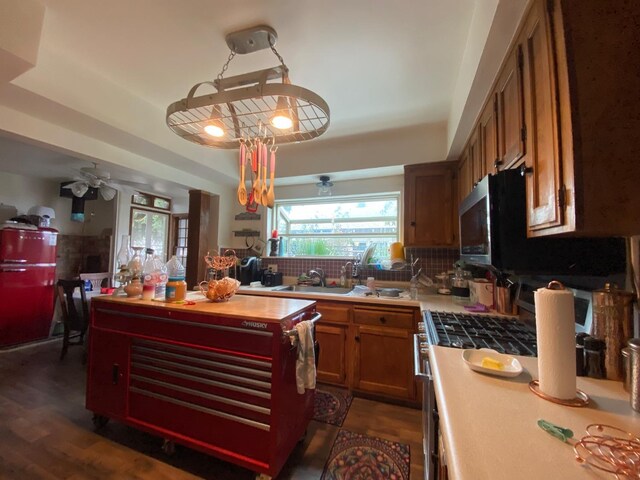 kitchen with a sink, brown cabinets, decorative backsplash, dark wood-style floors, and a raised ceiling