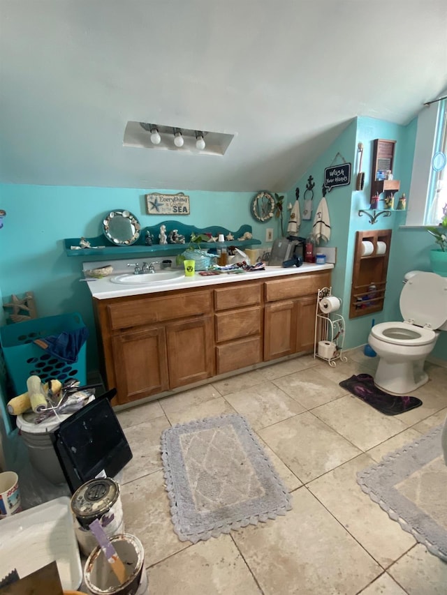 full bath featuring toilet, a sink, vaulted ceiling, tile patterned floors, and double vanity