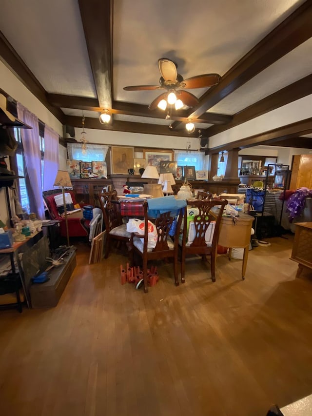 dining space with ceiling fan, beamed ceiling, and wood finished floors