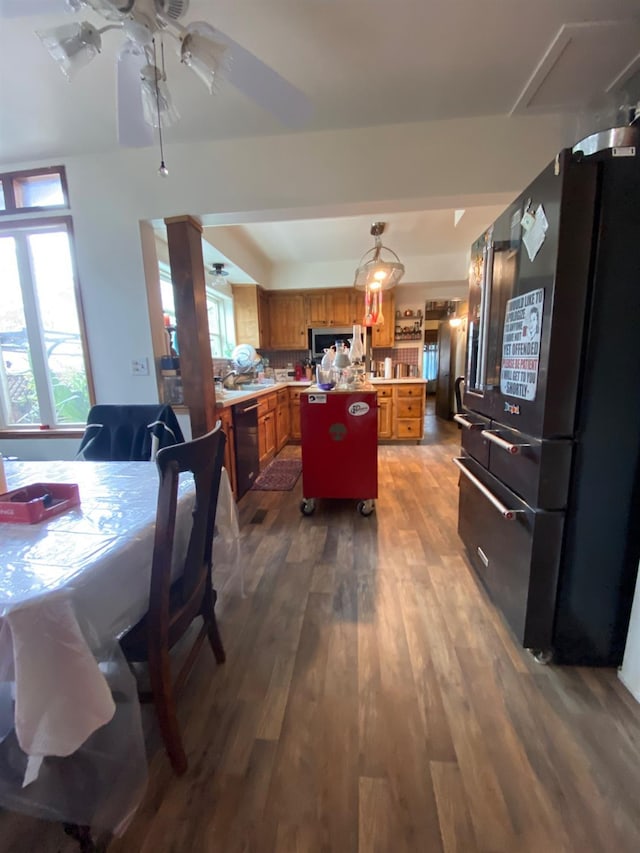 kitchen with black appliances, dark wood-style floors, brown cabinets, and a wealth of natural light