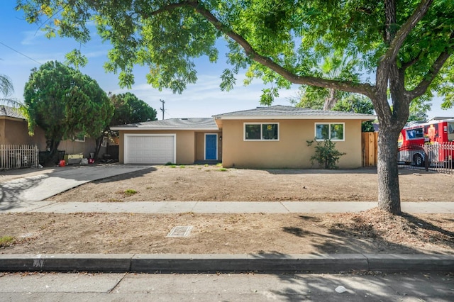 single story home featuring concrete driveway, an attached garage, fence, and stucco siding