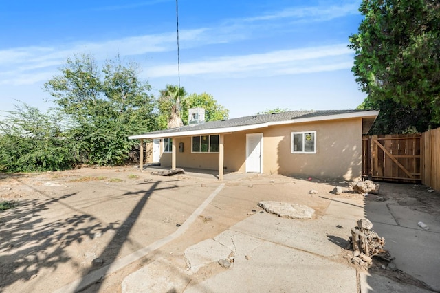 view of front of home with a gate, fence, a patio, and stucco siding