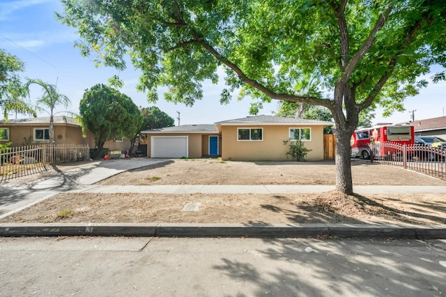 ranch-style house featuring driveway, an attached garage, fence, and stucco siding