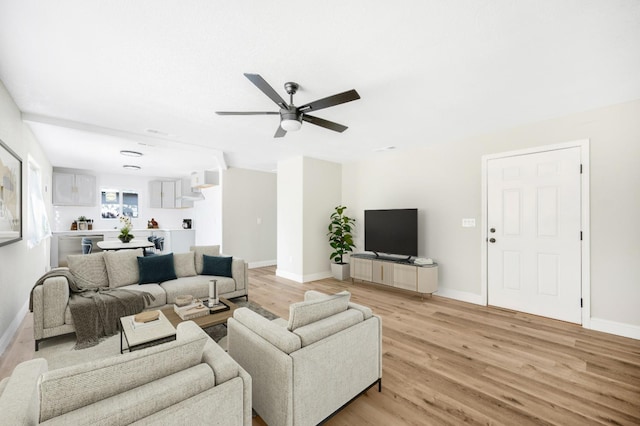 living room with baseboards, ceiling fan, and light wood finished floors