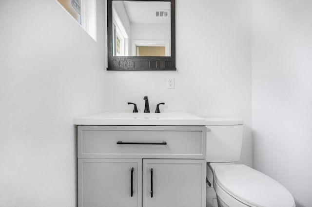 half bathroom with visible vents, vanity, and toilet