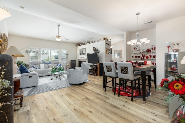 living room featuring visible vents, light wood-style flooring, and ceiling fan with notable chandelier