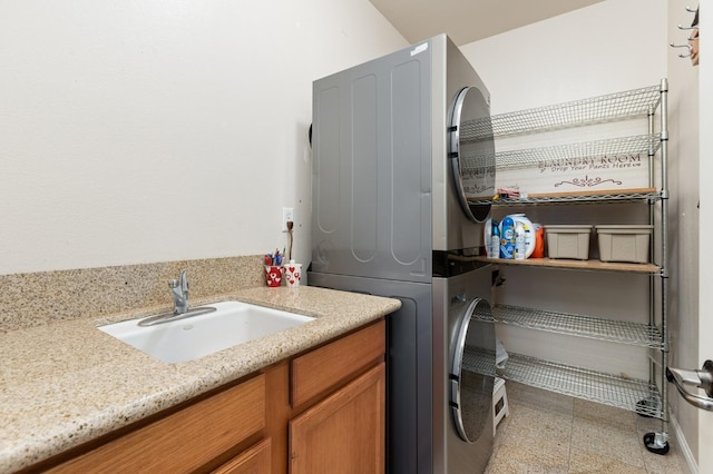 washroom featuring stacked washer and dryer, cabinet space, and a sink