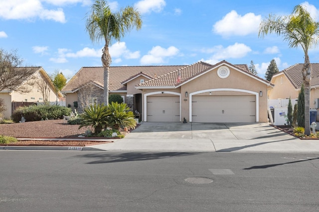 mediterranean / spanish-style house featuring a garage, concrete driveway, a tiled roof, fence, and stucco siding