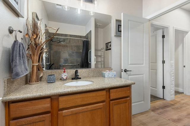 full bath featuring wood finished floors, tiled shower, and vanity