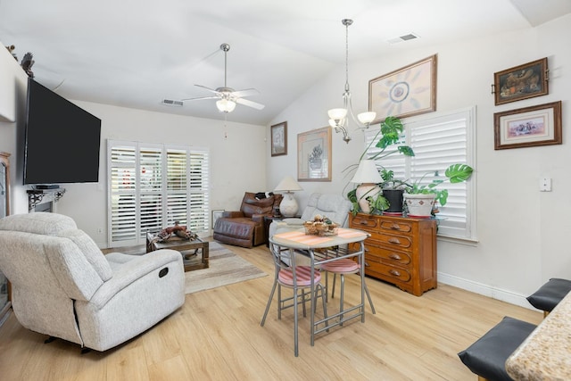 living room featuring baseboards, visible vents, vaulted ceiling, and wood finished floors