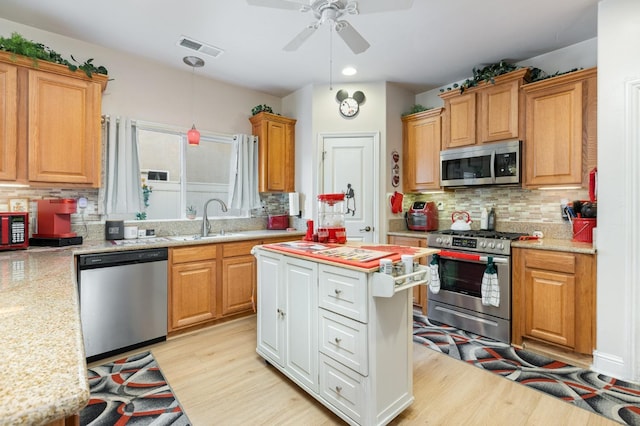 kitchen featuring stainless steel appliances, a sink, visible vents, light wood-type flooring, and backsplash