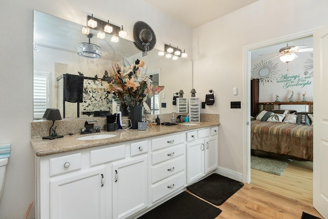 full bath with double vanity, wood finished floors, a sink, and connected bathroom