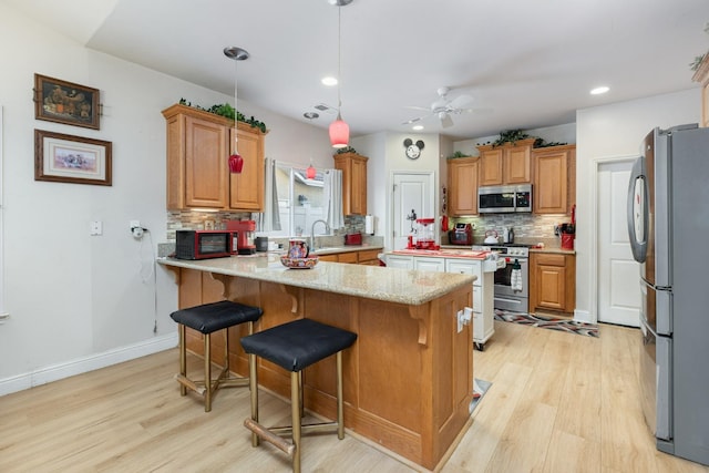 kitchen featuring light wood finished floors, a peninsula, appliances with stainless steel finishes, and decorative backsplash