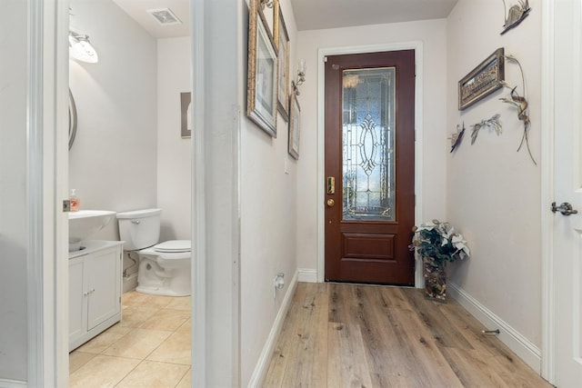 doorway featuring light wood finished floors, baseboards, and visible vents