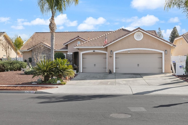 mediterranean / spanish house featuring concrete driveway, a tiled roof, an attached garage, and stucco siding