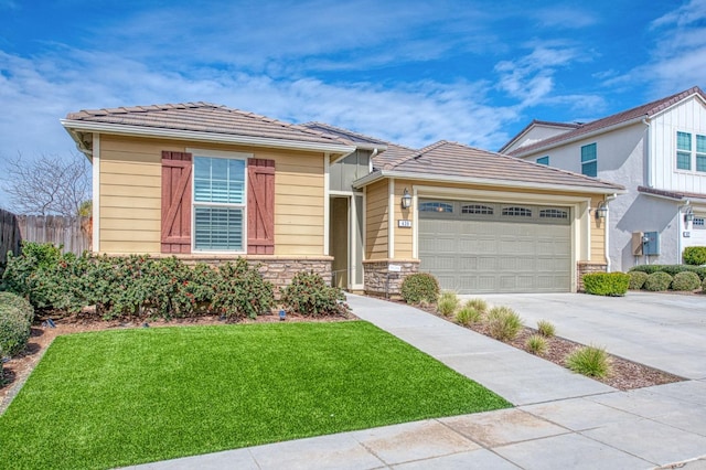 view of front facade with a garage, fence, stone siding, concrete driveway, and a front lawn