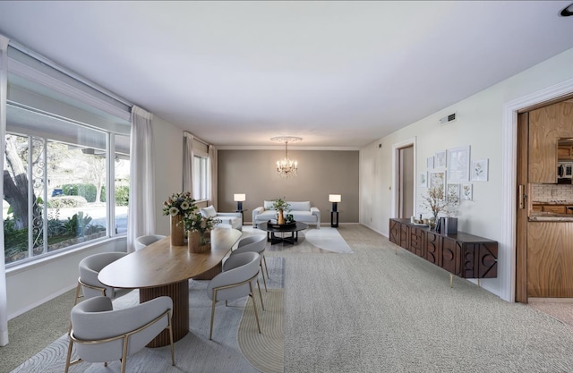 dining area featuring a chandelier, light carpet, and baseboards