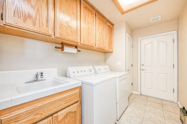 clothes washing area featuring cabinet space, light tile patterned floors, visible vents, washing machine and dryer, and a sink