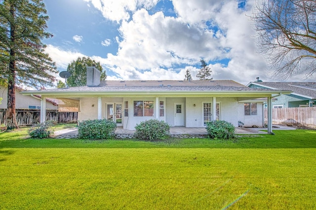 view of front facade with a chimney, a front yard, fence, and stucco siding