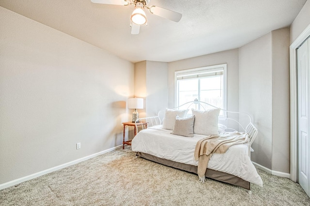 carpeted bedroom with ceiling fan, a textured ceiling, and baseboards