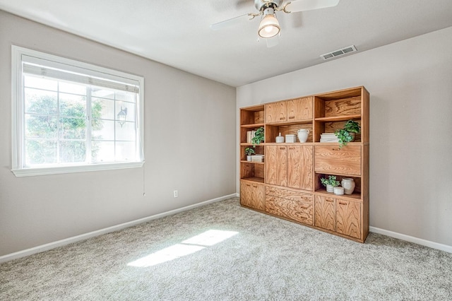 carpeted empty room with a ceiling fan, visible vents, and baseboards